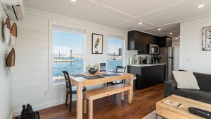 A compact living space with a dining area, kitchenette, and a view of the water.