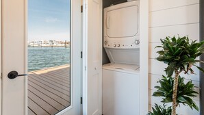A laundry room with a view of a dock and water, a washing machine, and a potted plant.