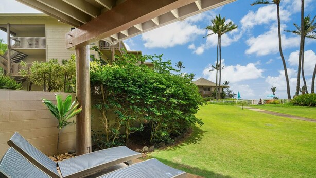 A covered outdoor seating area with a view of a building and a lawn.
