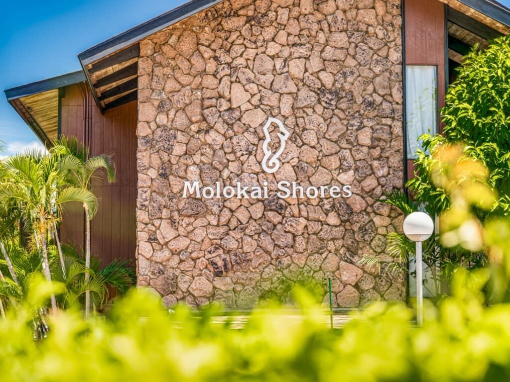 A building with a stone facade and the text "Molokai Shores" on it.