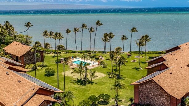 Un resort con varias edificaciones, una piscina y palmeras.