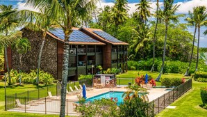Un edificio moderno con piscina, rodeado de exuberante vegetación y palmeras.