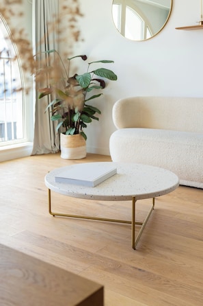 A modern living room with a round coffee table, a sofa, a potted plant, and a mirror on the wall. - Porte Bleue Marseille (Marseille)