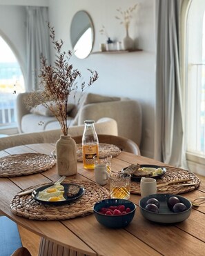 A dining table with placemats, plates of food, a bottle of drink, and a vase with dried flowers. - Porte Bleue Marseille (Marseille)