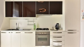 Une cuisine équipée d’une cuisinière, d’un four, d’un évier et de placards.