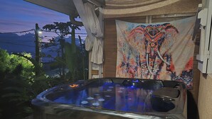 Un jacuzzi con un tapiz colorido, una terraza de madera y vistas al cielo.
