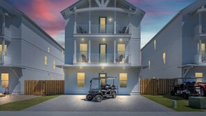A two-story residential building with a balcony, a driveway, and a golf cart parked in front. - "Blue Pearl"| LUXURY HOME | PRIVATE POOL | SPA | 6 SEAT CART (Miramar Beach)