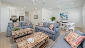 A modern living room with grey sofas, a wooden coffee table, and a ceiling fan. - "Blue Pearl"| LUXURY HOME | PRIVATE POOL | SPA | 6 SEAT CART (Miramar Beach)