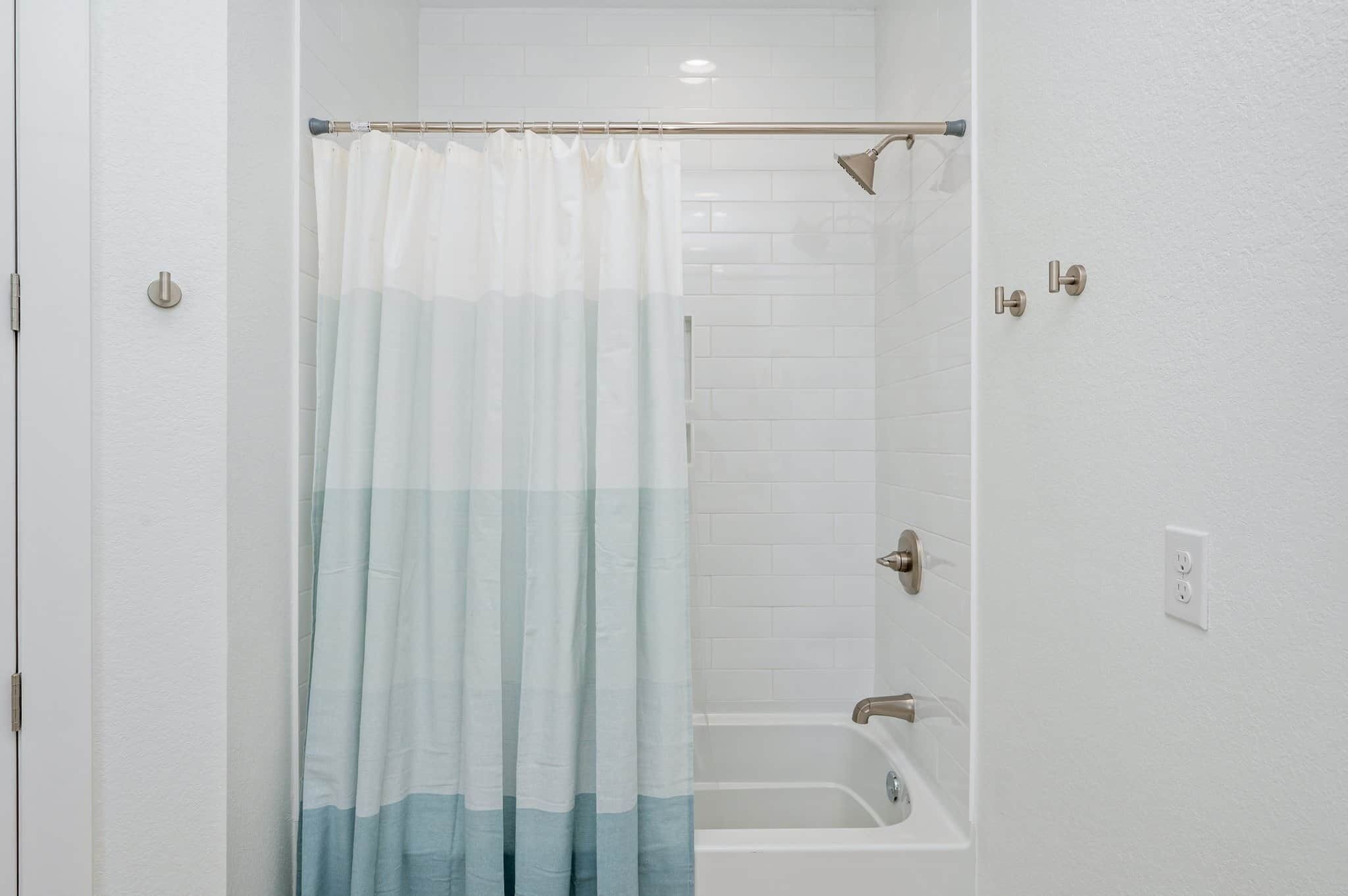 Une salle de bain avec une douche, une baignoire et un rideau.