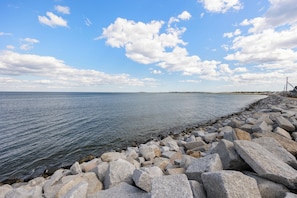 A rocky shoreline with a calm sea and a clear sky.