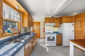 A kitchen with wooden cabinets, a stainless steel sink, a stove, and a refrigerator.