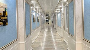 A long hallway with marble floors and blue-framed walls, leading to a door at the end. - AFSONA HOTEL (Bukhara)