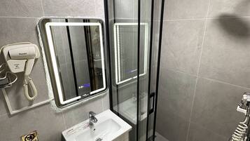 Un baño moderno con ducha de vidrio, lavamanos con tocador y espejo con iluminación integrada.