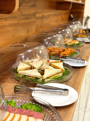 A buffet table with sandwiches, salads, and other dishes. - AFSONA HOTEL (Bukhara)