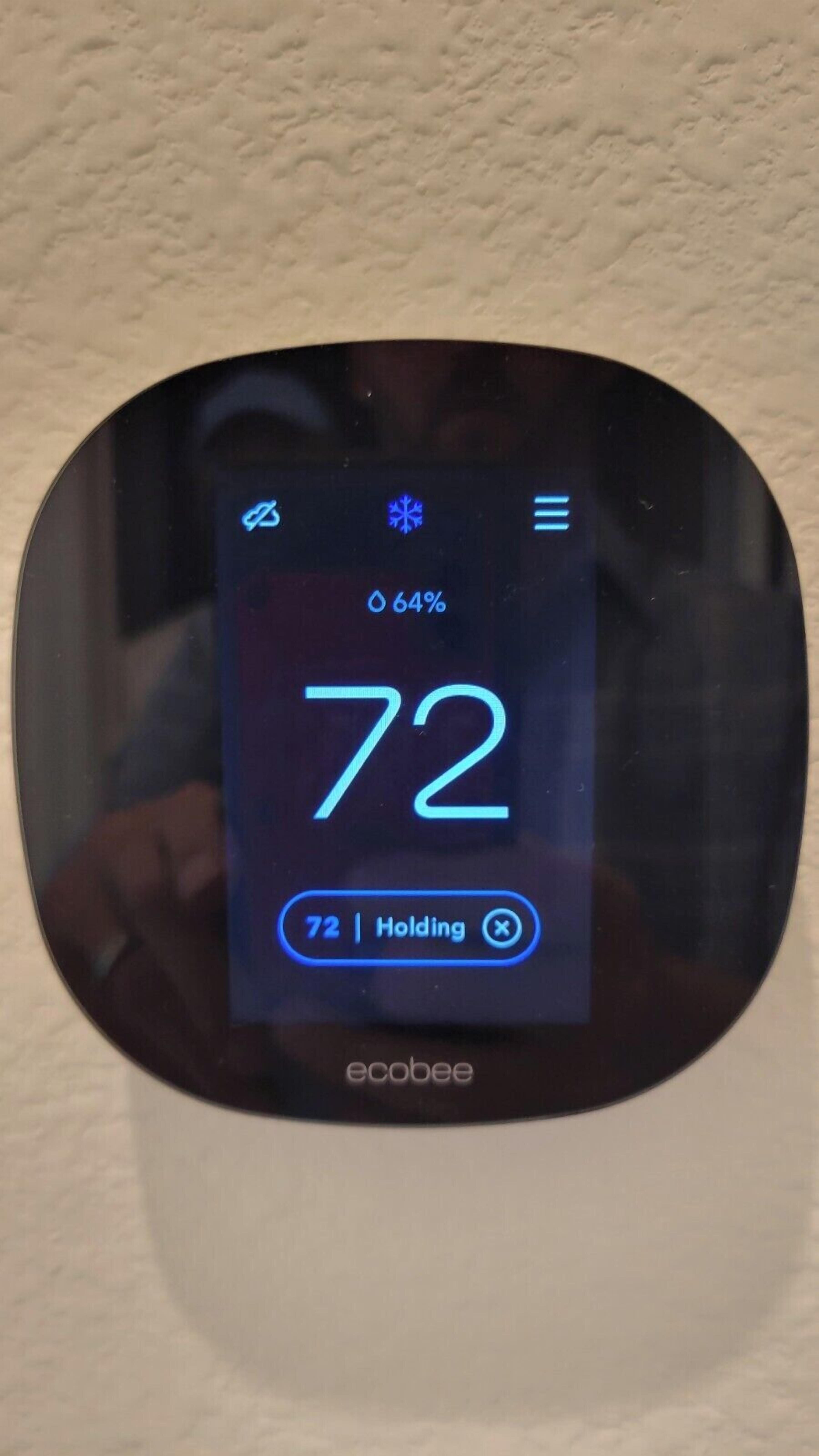 A thermostat displaying a temperature of 72°F with a 64% humidity reading.
