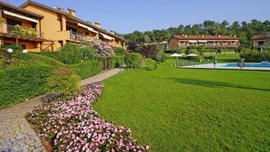 Ein Hotel mit Schwimmbad, gepflegter Rasenfläche und einem blumenbehangenen Weg.