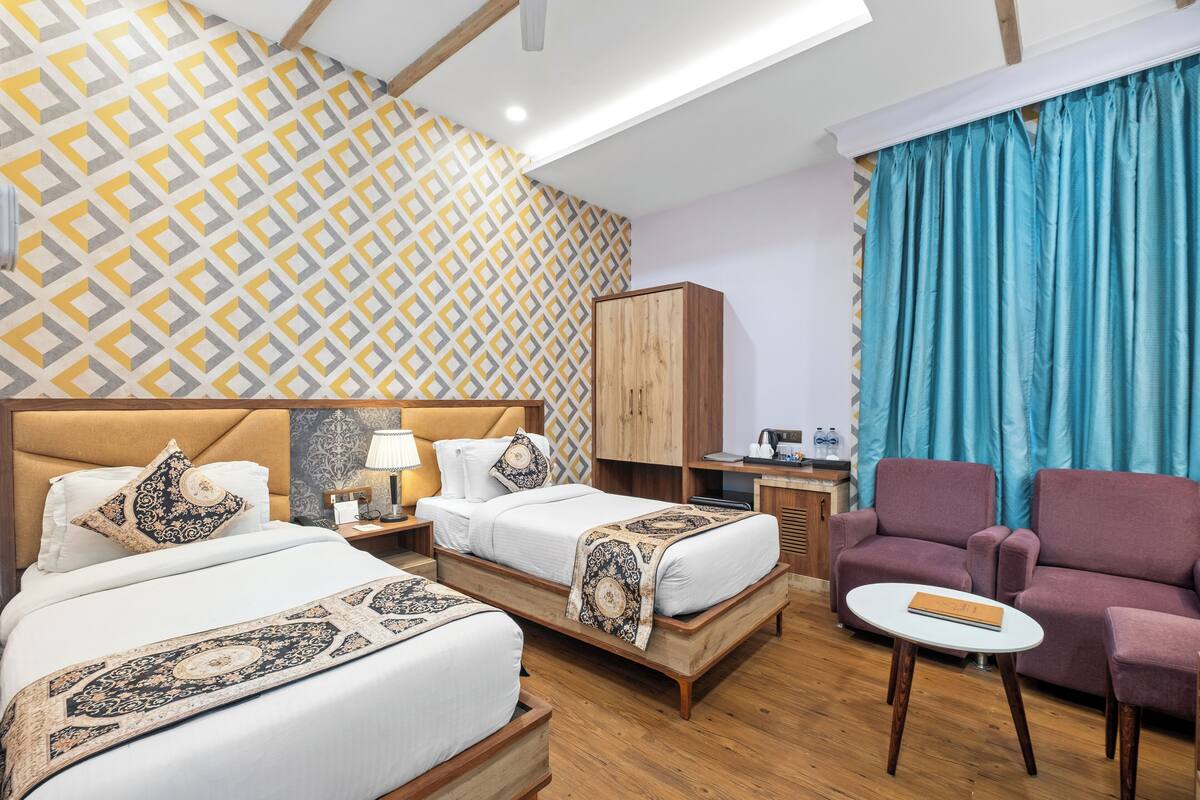 Habitación de hotel con dos camas, un sofá, una mesita y un armario.