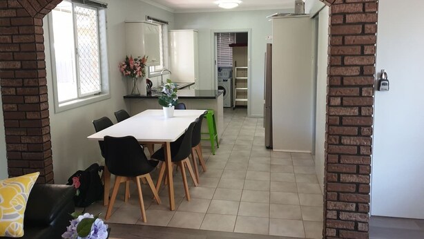 A dining area with a brick archway, a white table, black chairs, and a green stool.
