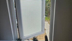 Una habitación con ventana, un escritorio y dos plantas en macetas.
