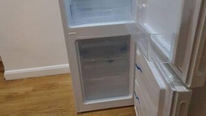 Un refrigerador abierto con varios estantes y un compartimento congelador.