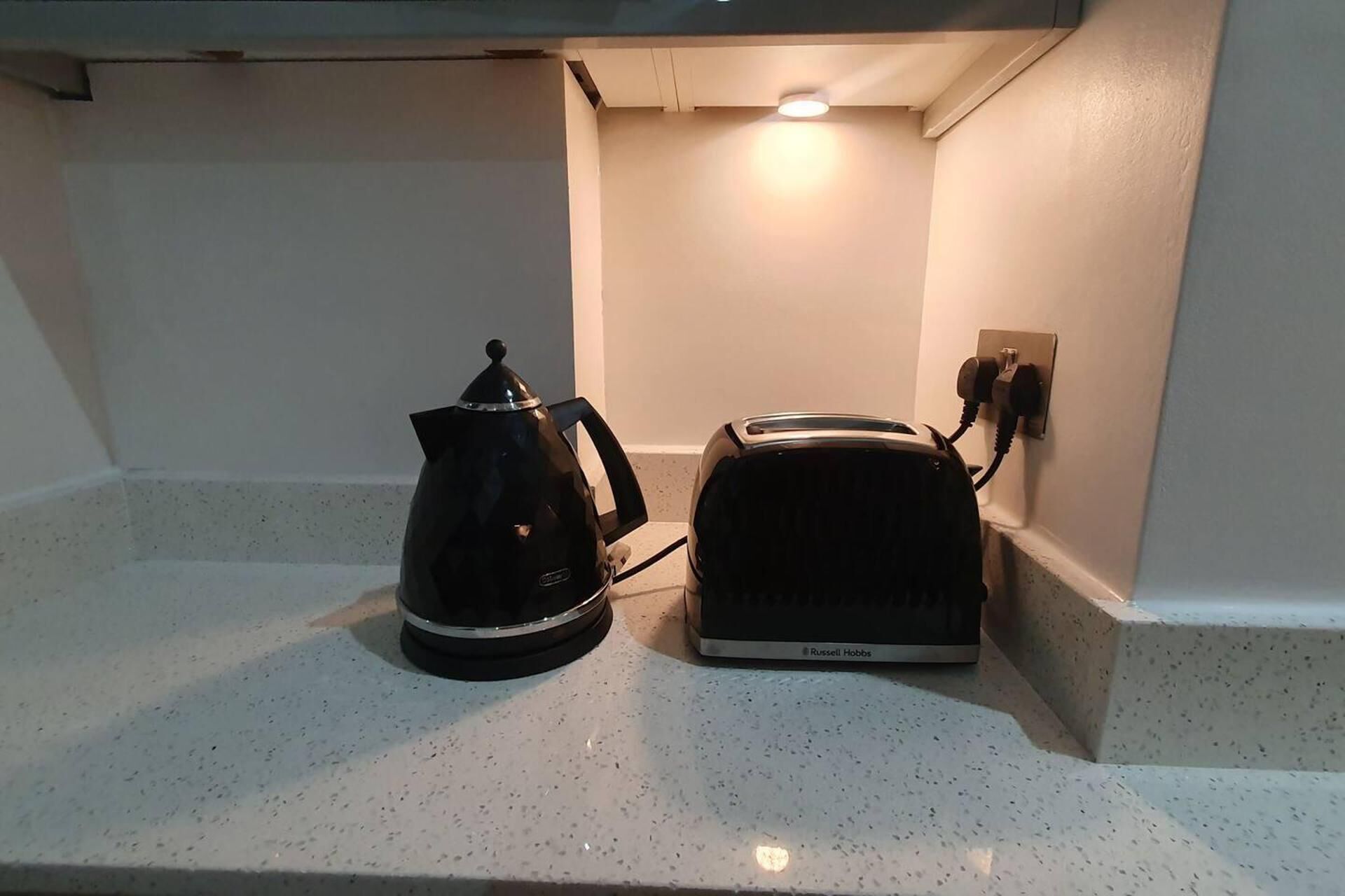 A kitchenette with a coffee maker and a toaster on a countertop.
