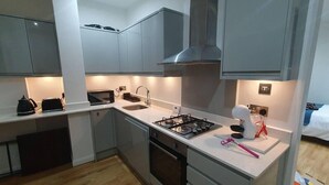 Una cocina moderna con gabinetes grises, una estufa a gas, un microondas y una tetera.