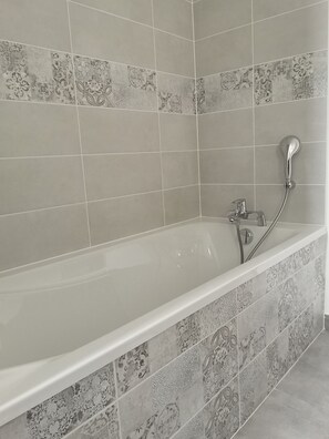 Bathroom features a bathtub with a chrome faucet and handheld showerhead.