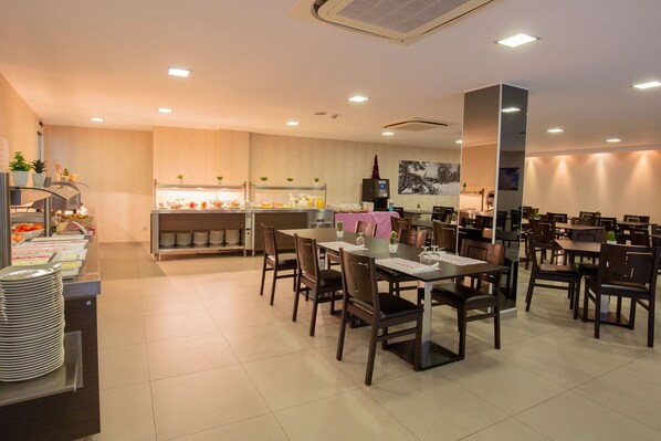 A modern dining area with multiple tables and chairs, a buffet counter with food and beverages, and a kitchen in the background. - Hotel del Pui by Nexta (La Massana)