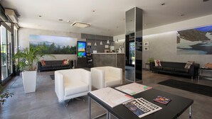 A modern lobby with a reception desk, seating area, and a large mural. - Hotel del Pui by Nexta (La Massana)