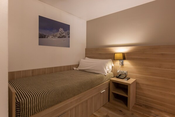 A small, neatly arranged bedroom with a single bed, a bedside table with a lamp, and a framed picture on the wall. - Hotel del Pui by Nexta (La Massana)