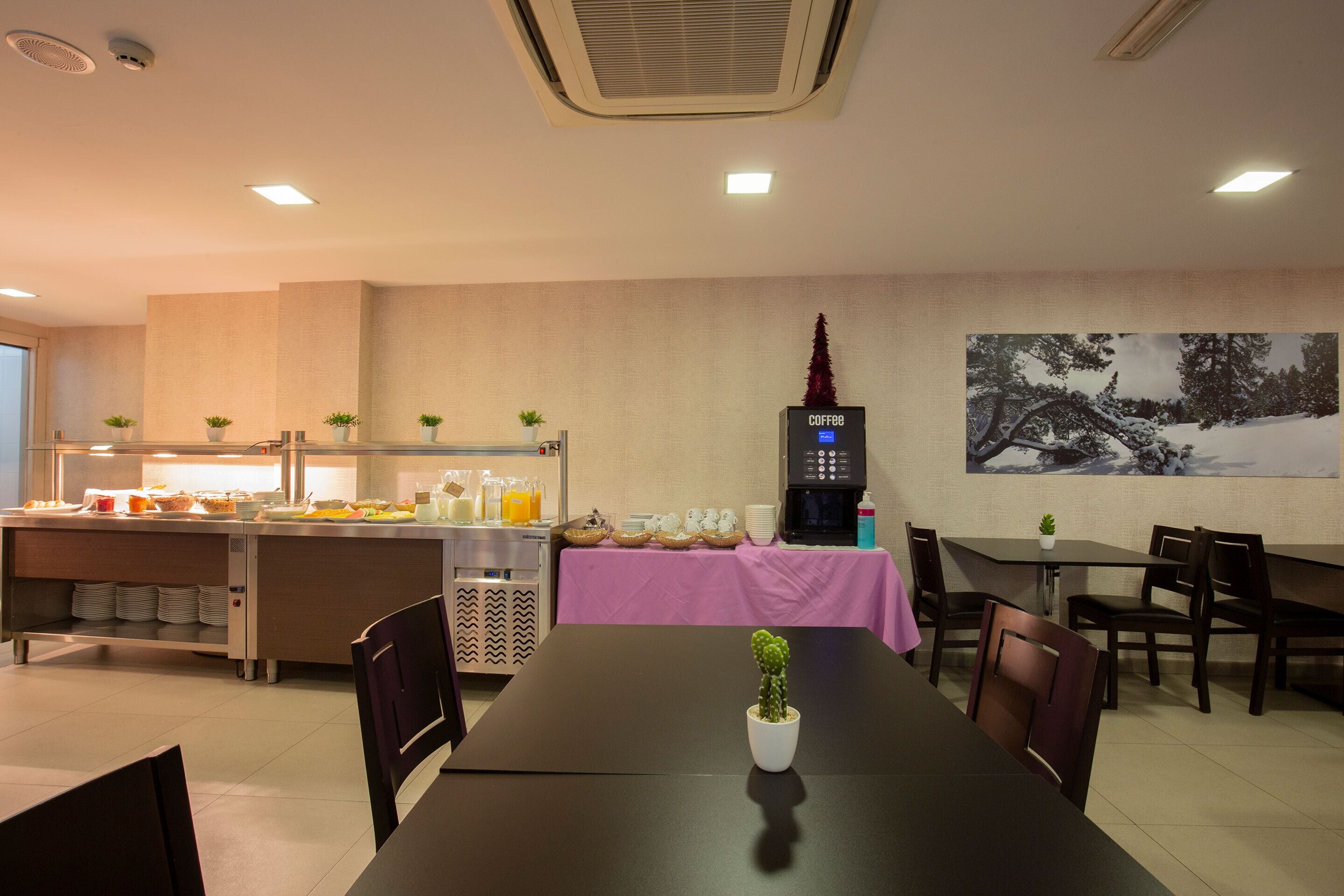 Un comedor con una mesa larga, sillas, una máquina de café y un mostrador tipo bufé con comida y bebidas.
