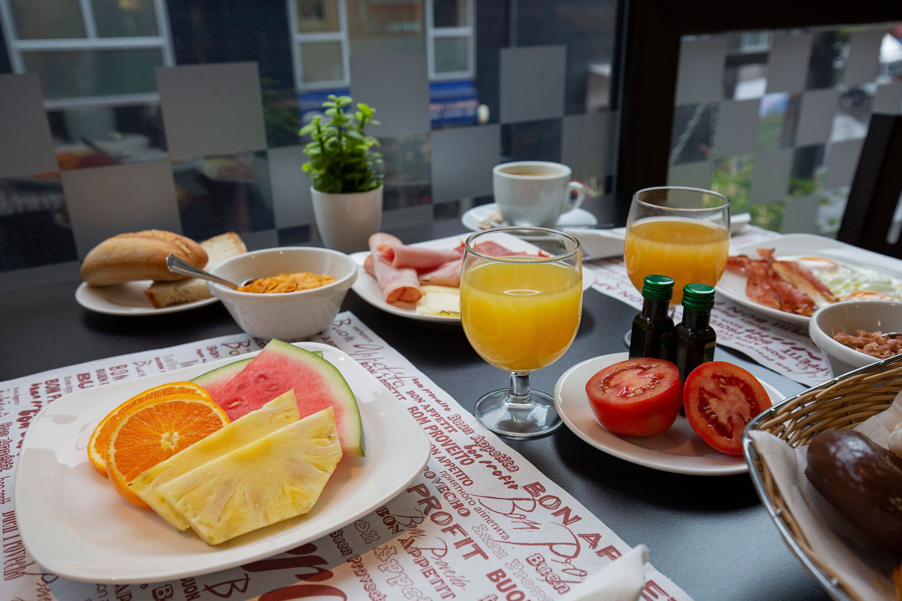 A breakfast table with plates of food, a glass of orange juice, and a cup of coffee.