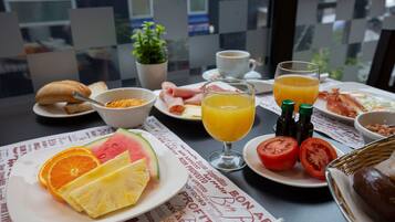 A breakfast table with plates of food, a glass of orange juice, and a cup of coffee.