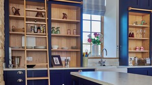 Una cocina con armarios azul oscuro, una escalera de madera y una ventana con flores.