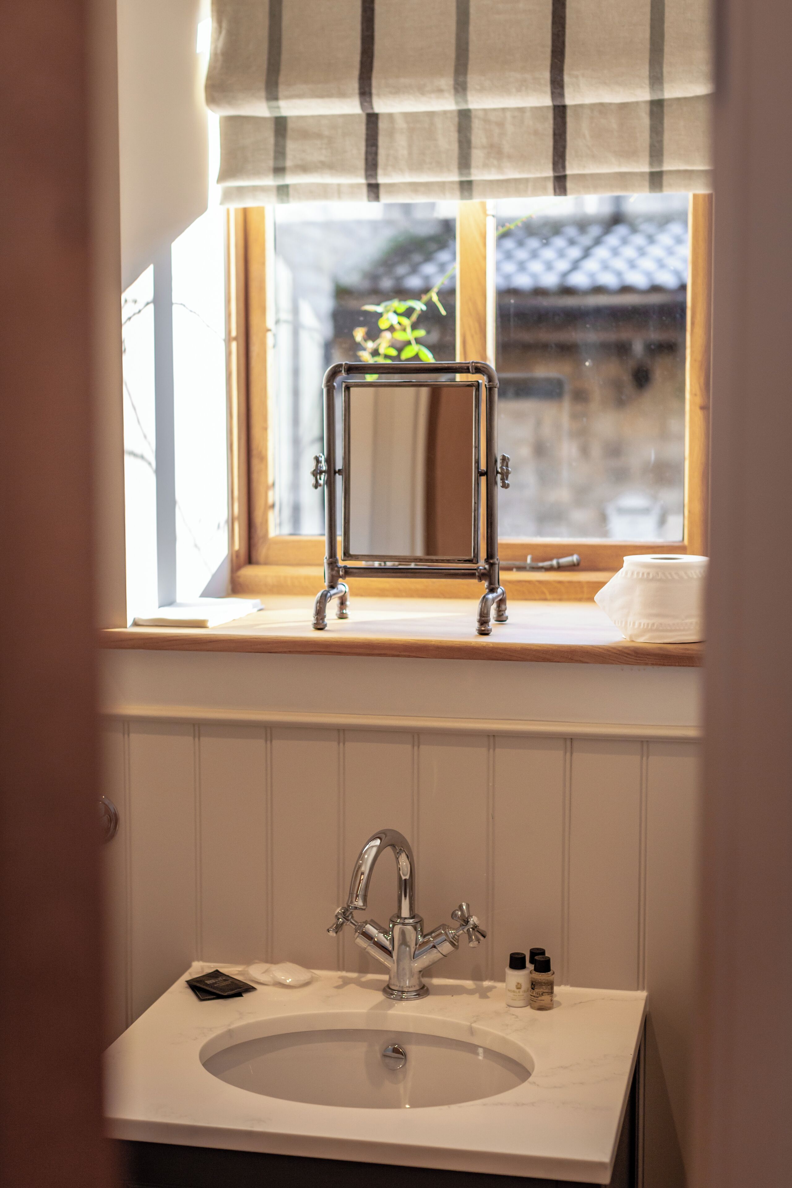 Un baño con lavamanos, espejo y ventana.