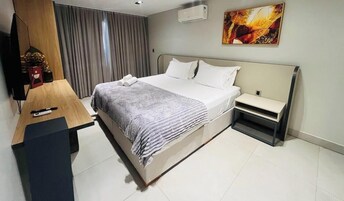 Quarto de hotel com cama, mesa de cabeceira e escrivaninha com cadeira.