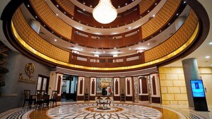 A grand lobby with a circular floor design, a central chandelier, and a reception desk. - Nine Tree Luxury Hotel & Suites (Lahore)
