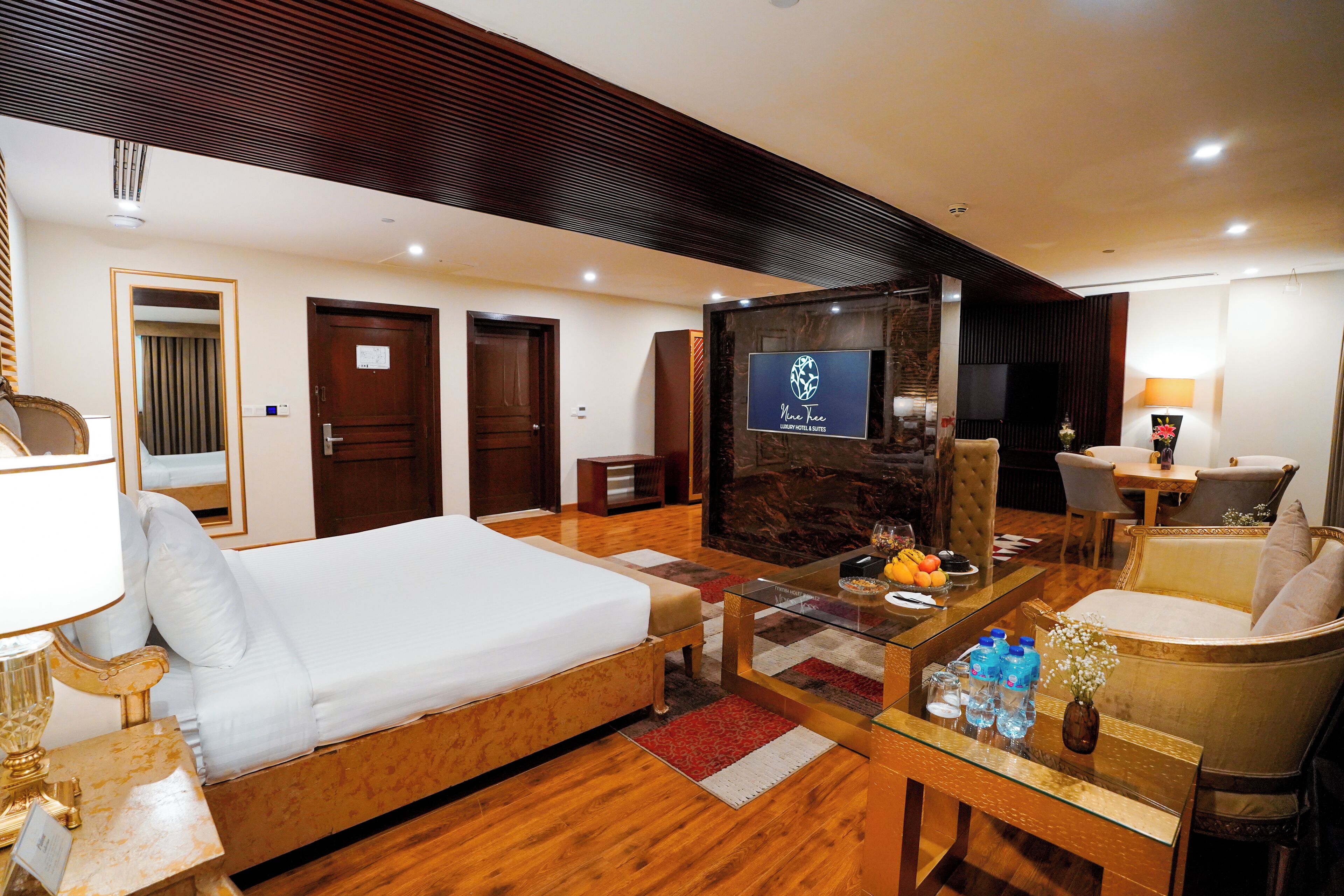 Une chambre d’hôtel comprenant un lit, une télévision, une table basse et un coin salon avec un fauteuil et un canapé.