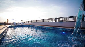 A swimming pool with a clear view of the water, a railing, and a few lounge chairs. - Nine Tree Luxury Hotel & Suites (Lahore)