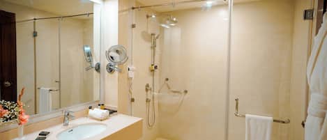 Um banheiro moderno com um espelho grande, duas pias, chuveiro com porta de vidro e porta-toalhas.