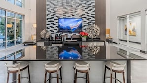 A modern kitchen with a large island, bar stools, and a flat-screen TV mounted on a textured wall. - Unwind at Cityline - Premium 1BR in Dallas (Dallas)