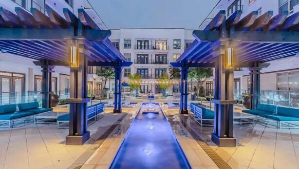 A modern outdoor pool area with blue seating and a central water feature. - Unwind at Cityline - Premium 1BR in Dallas (Dallas)