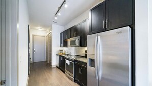 A modern kitchen with dark cabinets, stainless steel appliances, and a wooden floor. - Unwind at Cityline - Premium 1BR in Dallas (Dallas)