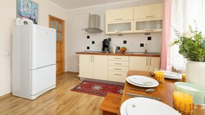 A compact kitchen with a refrigerator, a stove, and a microwave. There is a dining table with plates, glasses, and a vase with flowers. - Family Apartment in Zakopane | Parking | Air Conditioning (Zakopane)