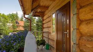 A wooden log cabin with a balcony, potted plants, and a door. - Family Apartment in Zakopane | Parking | Air Conditioning (Zakopane)