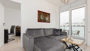 Una sala de estar moderna con un sofá seccional gris, una mesa de centro de madera y un amplio ventanal con vistas a la ciudad.