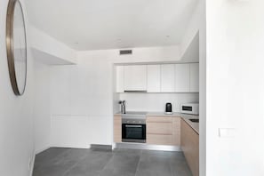 A modern kitchen with white cabinets, a built-in oven, and a microwave.