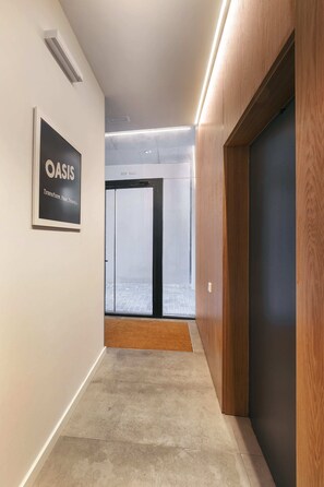 A corridor with a wooden wall, a framed sign, and a door leading to a room with a view.