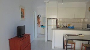 A modern kitchen with white cabinets, a refrigerator, and a small dining area with two chairs.