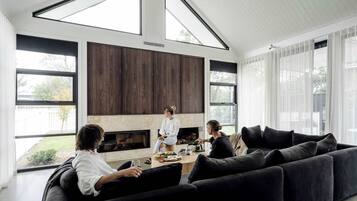 Uma sala de estar moderna com lareira, janelas amplas e painéis de madeira escura.